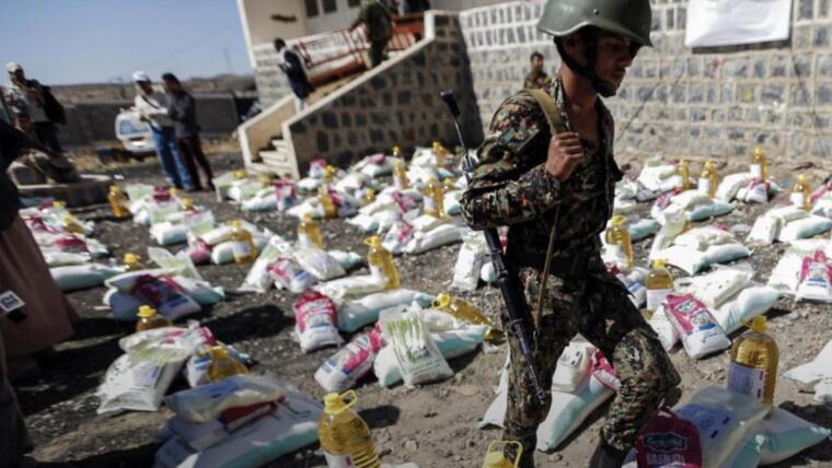 A Houthi-affiliated soldier walks among humanitarian aid supplies in a displaced persons camp